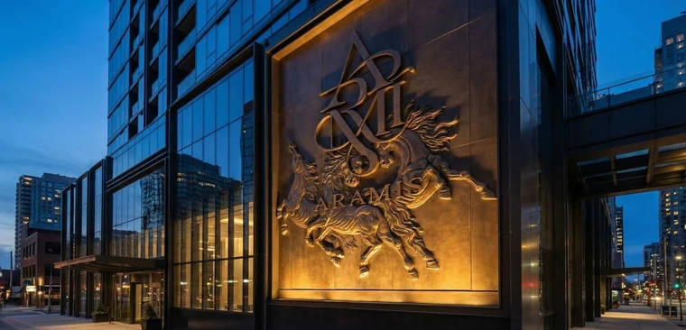 The Aramis crest illuminated on an architectural facade.