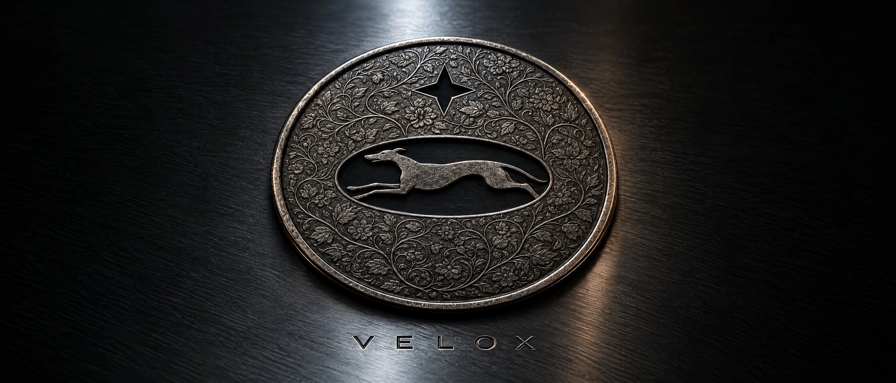 The Velox greyhound mark embossed on a metal medallion.